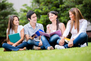 Happy group of students sitting at the park talking